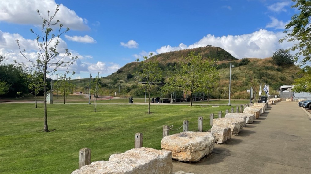 מדשאה גדולה לצד מגרש החנייה של הפארק ומדרום בולט הר הזבל (תל קנה)